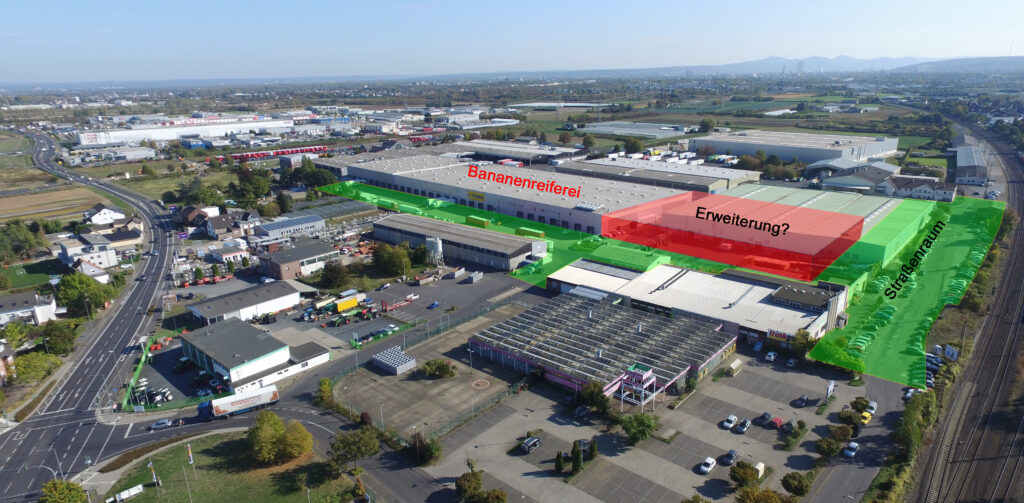 Luftaufnahme eines Industriekomplexes mit markierten Zonen mit den Bezeichnungen "Bananenreiferei", "Erweiterung" und "Stichstraße", wobei bestimmte Bereiche grün und rot hervorgehoben sind.
