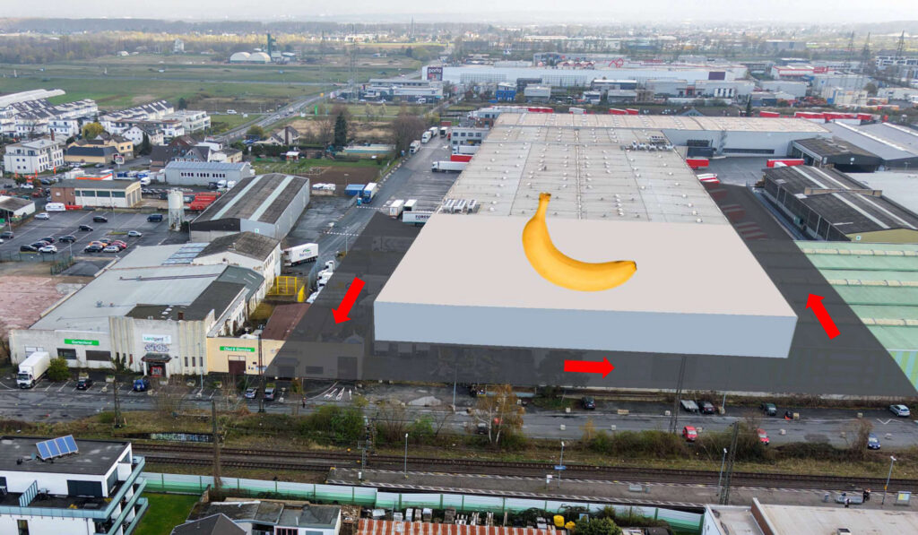 Luftaufnahme eines Industriegebiets mit einer großen Lagerhalle, überlagert von einer digitalen Illustration einer Banane und roten Pfeilen, die die Abmessungen auf dem Dach angeben.